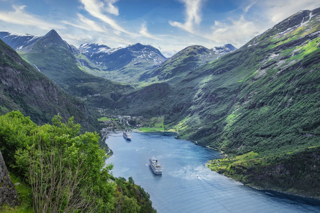 A breathtaking high angle view of cruise ships in Geirangerfjord surrounded by lush mountains.