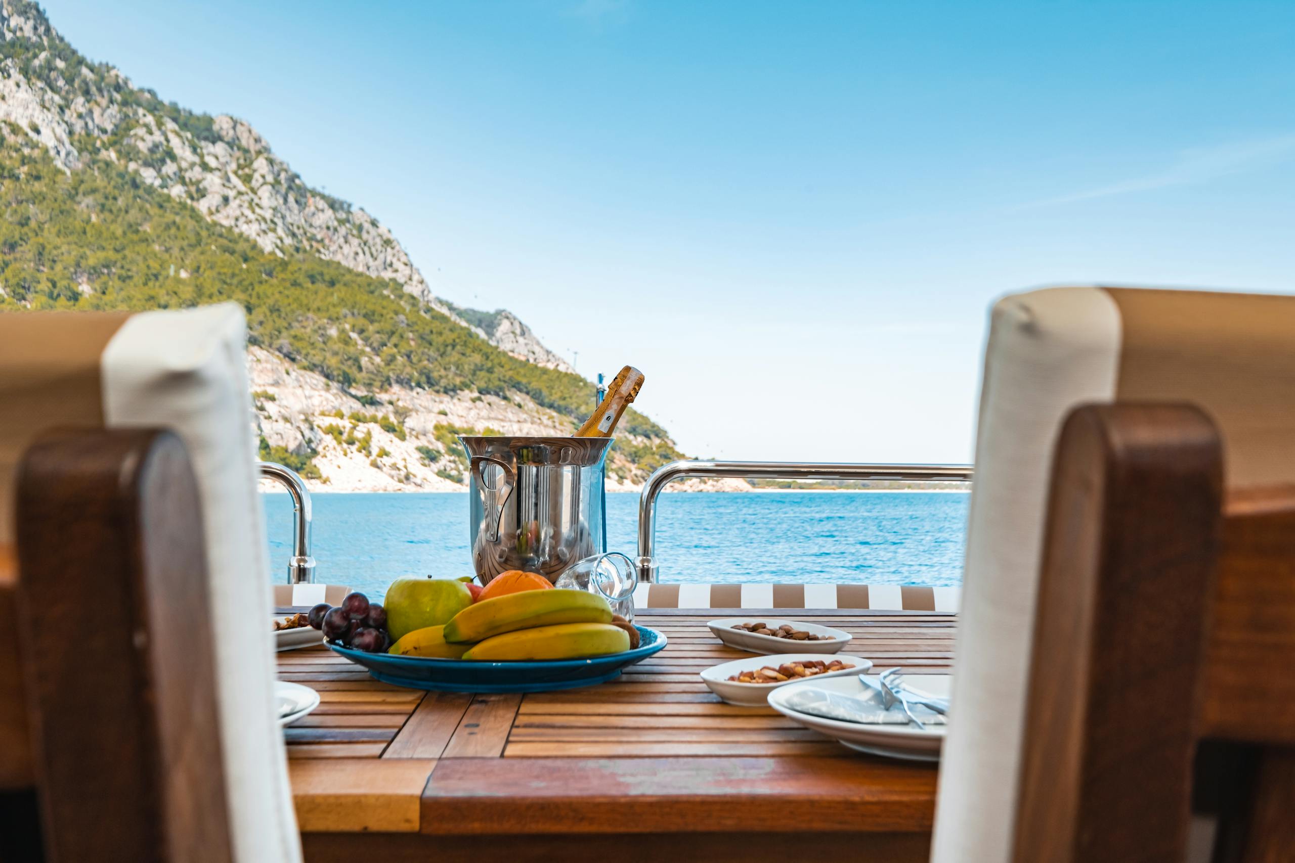 Luxurious yacht dining setup with fruits and champagne overlooking the Antalya coast, Türkiye.